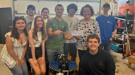 AAACU Team member presents a check to a member of the Cheboygan High School Senior Class of 2025
